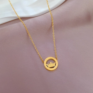 Close-up of gold crown pendant necklace on soft fabric background detail view