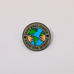 Detail of enamel pin showing hands holding the Earth with Save the Planet engraving
