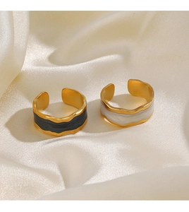 Detail view of gold wave rings with black enamel and marble inlay on silk fabric