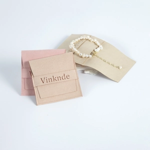 Détail de pochettes à bijoux en suédine rose et beige avec un bracelet de perles