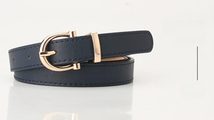 Detail of navy blue slim PU leather belt featuring a polished gold horseshoe buckle