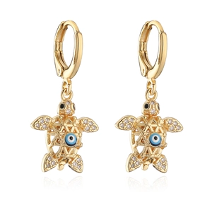 Gold-plated turtle earrings with evil eye center and shimmering crystal details on white base