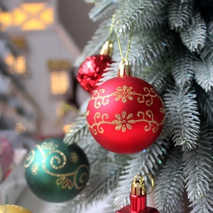 Red Christmas ornaments set with gold glitter patterns on a festive flocked tree
