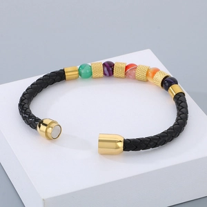 Dettaglio bracciale in pelle intrecciata con perle colorate e chiusura magnetica dorata