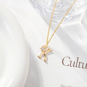Detail of gold letter K necklace with zircon pendant on a white ceramic plate