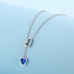 Detailed macro view of the silver necklace with open heart and blue sapphire heart charm
