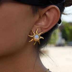 Close-up of 18K gold plated sun stud earring with white opal stone on model ear