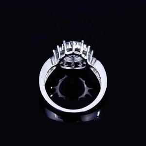 Macro shot of silver ring with round brilliant center stone and pavé halo setting