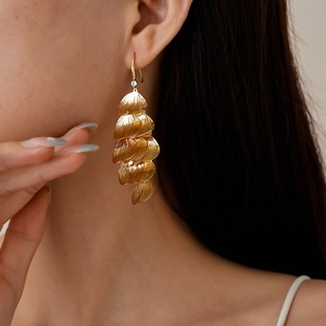 Close-up of gold layered petal tassel earrings with textured finish and crystal accent