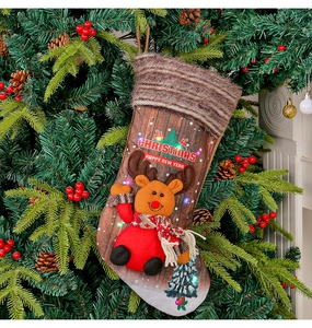 Détail d'une chaussette de Noël avec LED et motif élan suspendue à un sapin festif