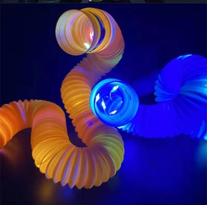 Close-up of glowing orange and blue LED pop tubes spiraling in a dark setting