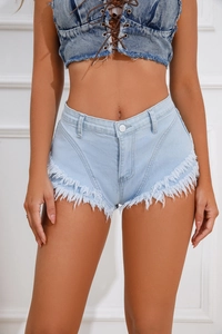 Dettaglio del tessuto denim blu chiaro con orlo a frange e bottoni in metallo lucido