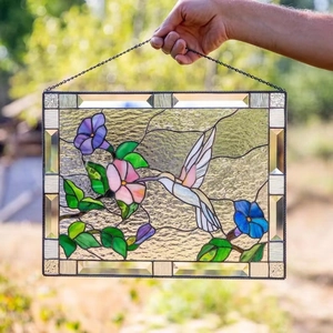 Close-up of stained glass hummingbirds and flowers panel with black metal frame