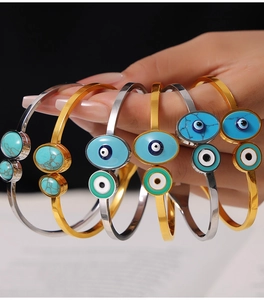 Close-up of bohemian titanium steel bangle with inlaid turquoise and colorful enamel evil eye