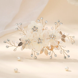 Detail of bridal hair clip with white fabric flowers, pearls and golden leaves