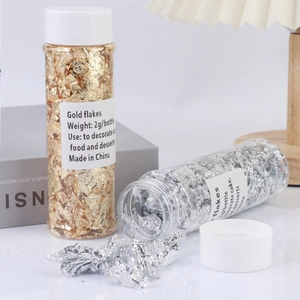 Detailed view of 2g gold and silver flakes in bottles for luxury cake and food decoration