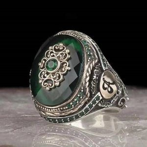 Macro detail of vintage silver ring with green oval gemstone and ornate carving