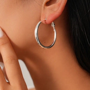 Close-up of model wearing polished silver hoop earrings with a minimalist circular design