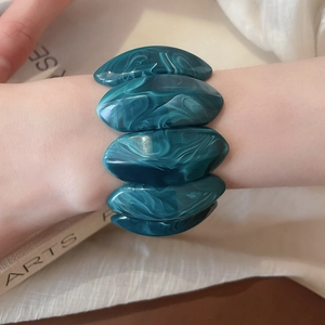 Detailed macro view of dark green marble pattern acrylic elastic bracelet on wrist