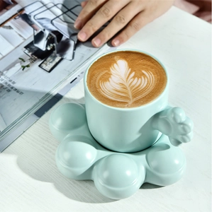 Detail of light blue ceramic coffee cup with cat paw handle on matching saucer