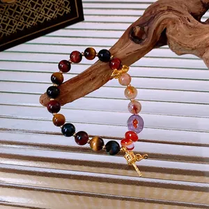Multicolor gemstone beaded bracelet with gold charms on a natural wood branch display