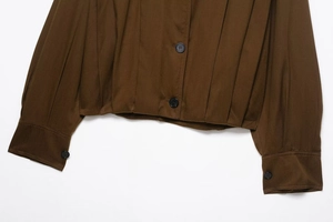 Detail of dark brown jacket showing pleated texture and premium black buttons