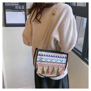Close-up of ethnic style canvas crossbody bag with colorful embroidery and tassels