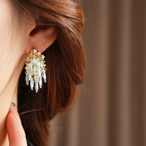 Gros plan de boucles d'oreilles dorées à pampilles avec cristaux bleu clair sur un modèle
