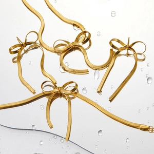 Golden bow necklace and earrings set in high-quality stainless steel on a water-drop surface