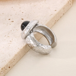 Bague en acier inoxydable à texture lave avec pierre noire sur fond de marbre