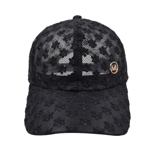 Détail de broderie florale en dentelle noire et logo M en métal doré sur la casquette