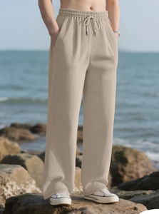 Outdoor shot of men's beige pleated wide-leg pants with vertical stripes and drawstring waist