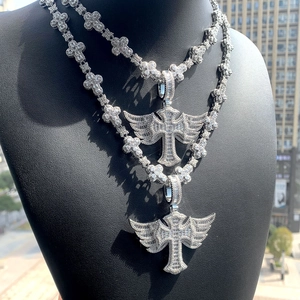 Macro view of silver-toned hip hop cross pendants with wings on a model's neck