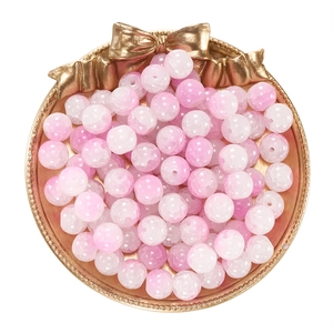 Macro detail of 10mm pink and white gradient cracked glass beads in a gold decorative tray