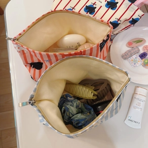 Détail de trousses à maquillage en coton rayé rose et bleu avec accessoires et soins