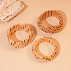 Close-up of three striped wooden bangles with geometric textures on beige background