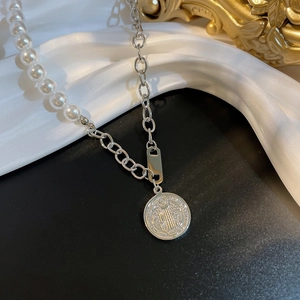 Detailed view of pearl and metal chain necklace with an embossed round pendant