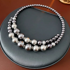 Détail d'un collier double rang avec perles dégradées grises et argentées sur un support