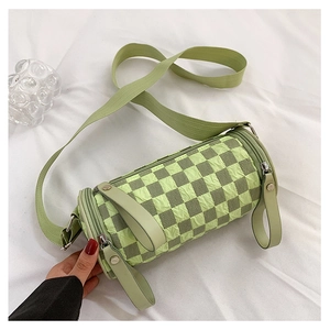 Macro shot of green checkerboard textured fabric and cylinder shape of the shoulder bag