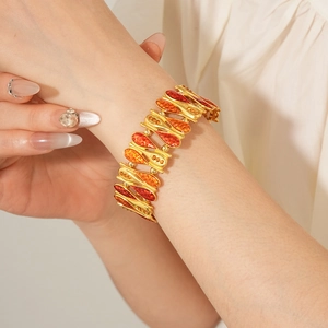 Detailed close-up of vintage gold bracelet with red enamel water drop charms and zircons