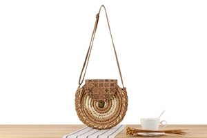 Detail of round woven crossbody bag with bohemian pattern on wooden surface