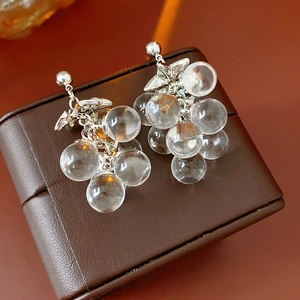 Detailed view of crystal grape tassel earrings on a vintage leather jewelry display box