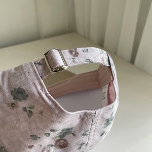 Détail arrière d'une casquette fleurie avec boucle métallique argentée ajustable