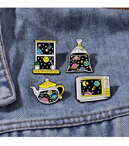 Detailed view of four space-themed enamel pins featuring star motifs on blue denim fabric
