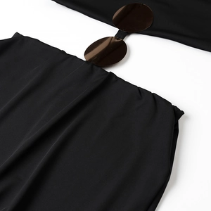 Detail of black dress featuring stylish cutout design with two gold metal ring connectors