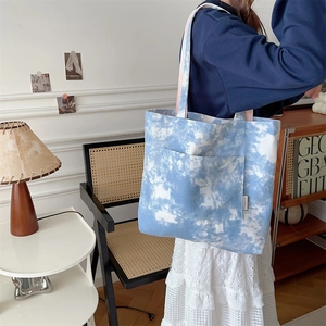 Dettaglio della borsa tote in tela tie-dye blu e bianca con tasca frontale e tracolla