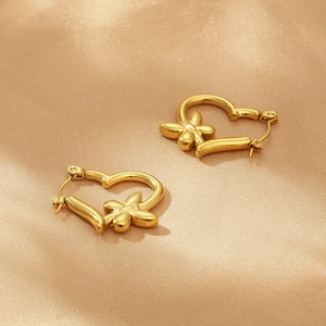 Elegant gold butterfly heart hoop earrings on silky fabric background with metallic texture