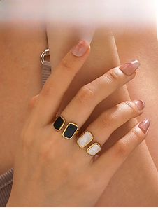 Detail view of a set of four geometric gold rings with black and marble enamel accents