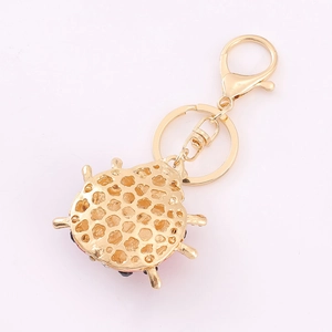 Golden ladybug keychain with red rhinestones and honeycomb pattern on white backdrop