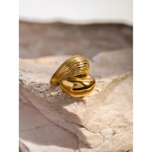 Close-up of 18k gold teardrop ring with shell texture on natural beige stone base